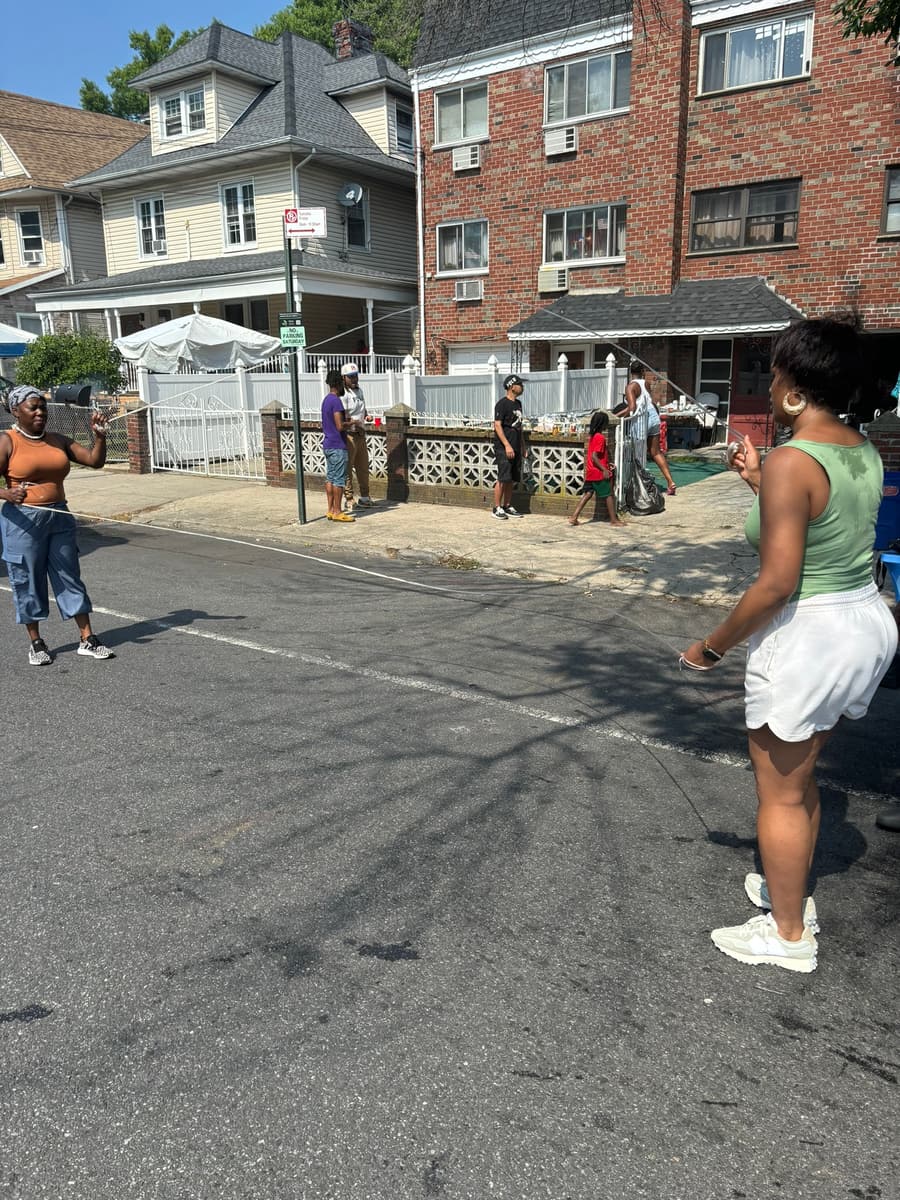 Neighbors turning a double dutch rope in the middle of the closed street