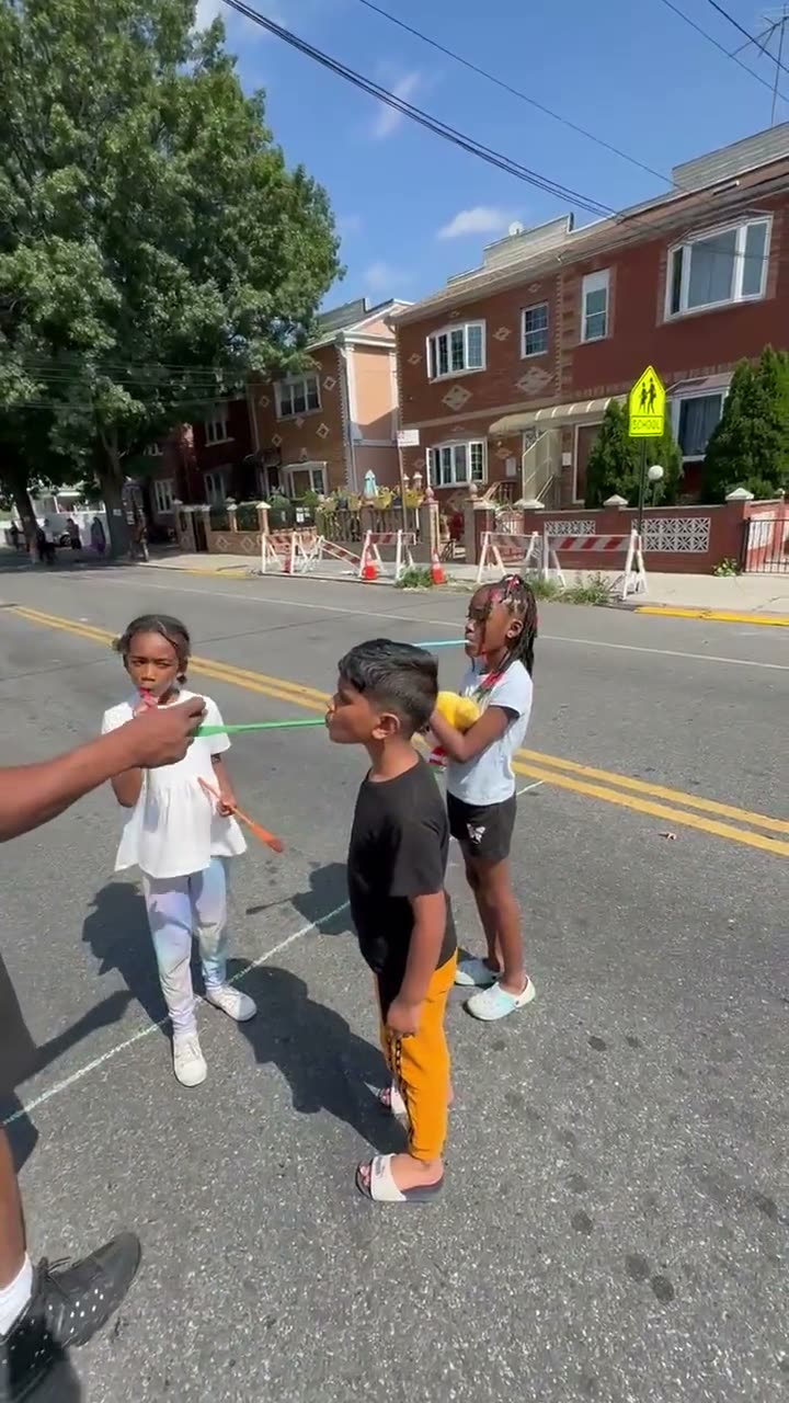 Kids playing with paddle-ball sets in the middle of the closed avenue