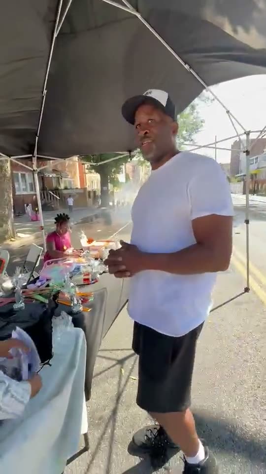 Under the canopy at the giveaway tables, with the block out on the street behind