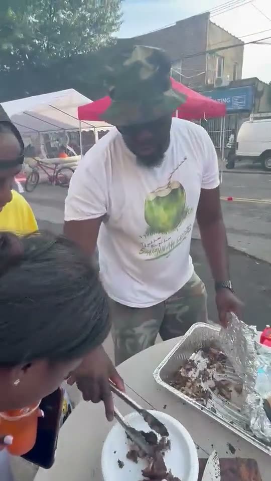 Food being served out of foil trays at the tables under the canopies on the closed street